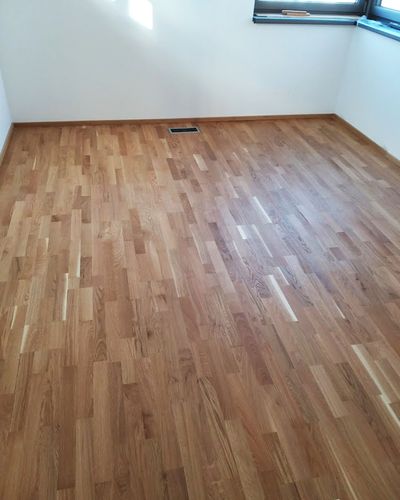 Dubová parketová podlaha v prázdnej miestnosti s veľkými oknami